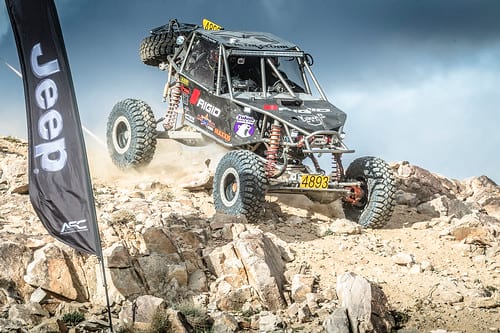 ATV off-roading heading downhill with Jeep flag in foreground /><figcaption>Image via <a href=