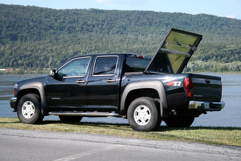 Black Chevy Colorado at lake with truck cover accessory open